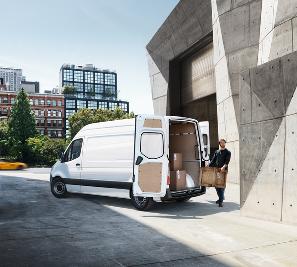 Informationen Versand Ein weißer Mercedes Sprinter wird mit Paketen beladen.